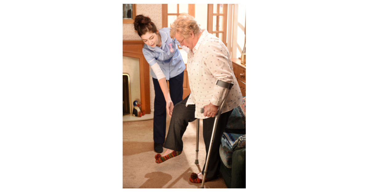 Physiotherapist guiding a patient with functional walking rehabilitation in their home environment